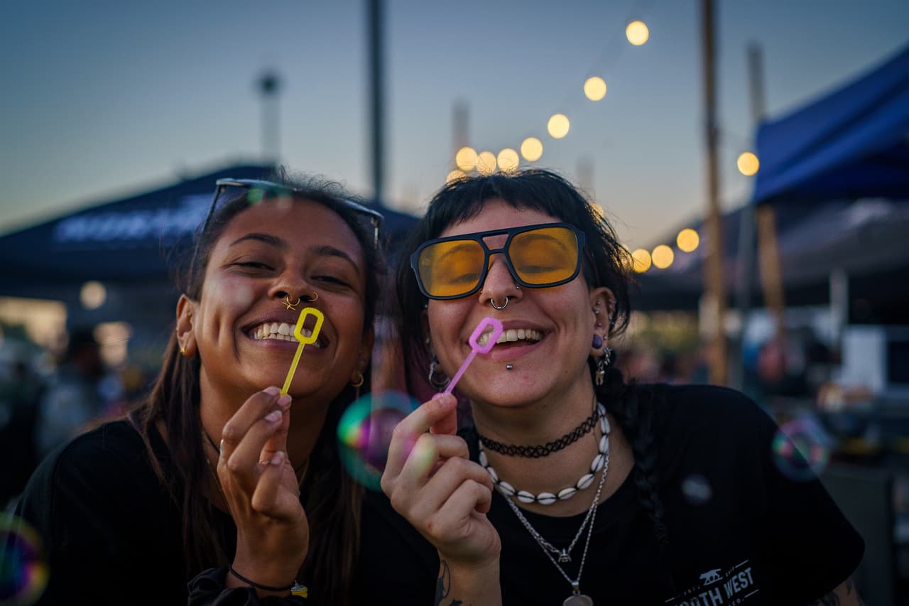 Two friends blowing bubbles at a festival