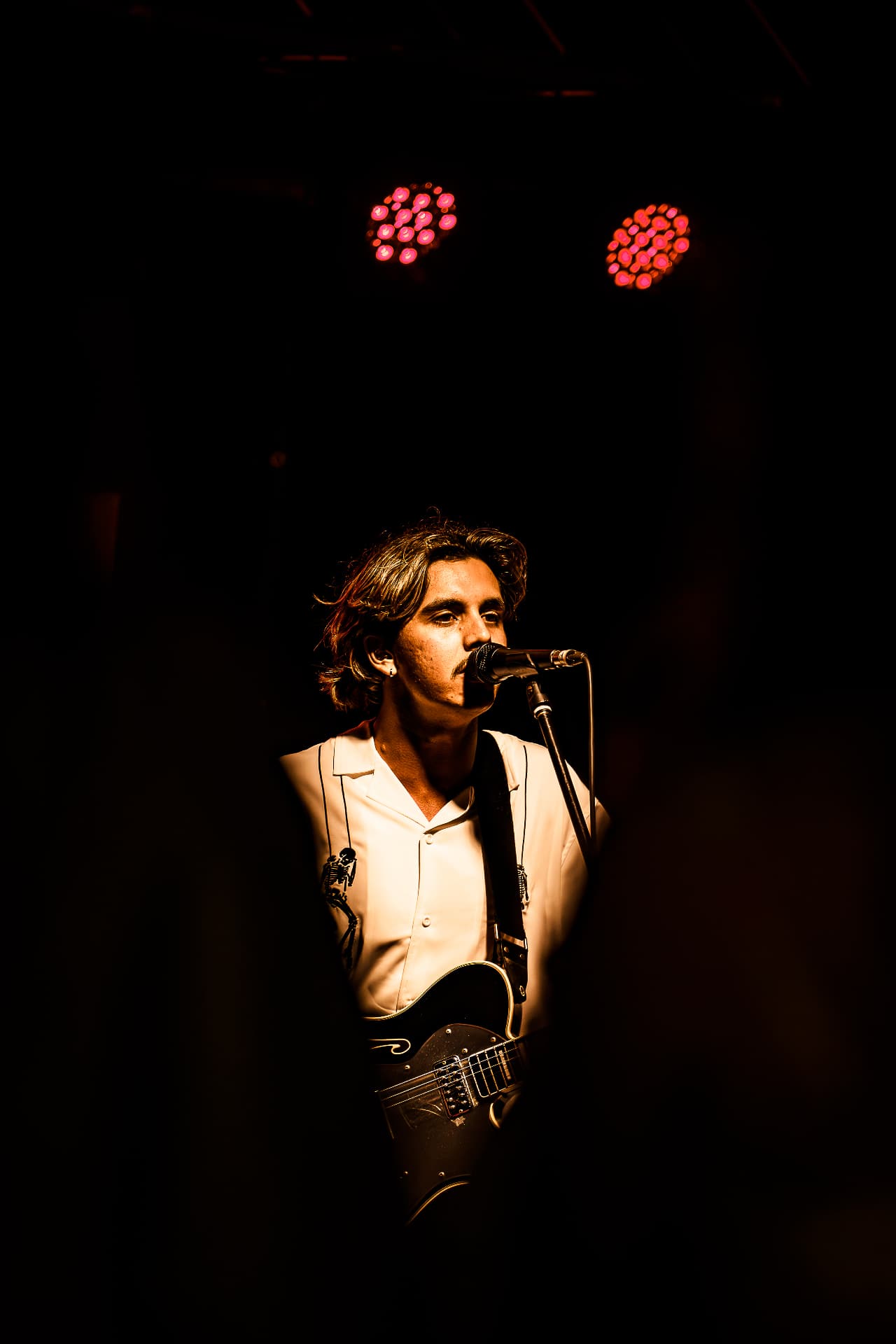 Singer with guitar under stage lights