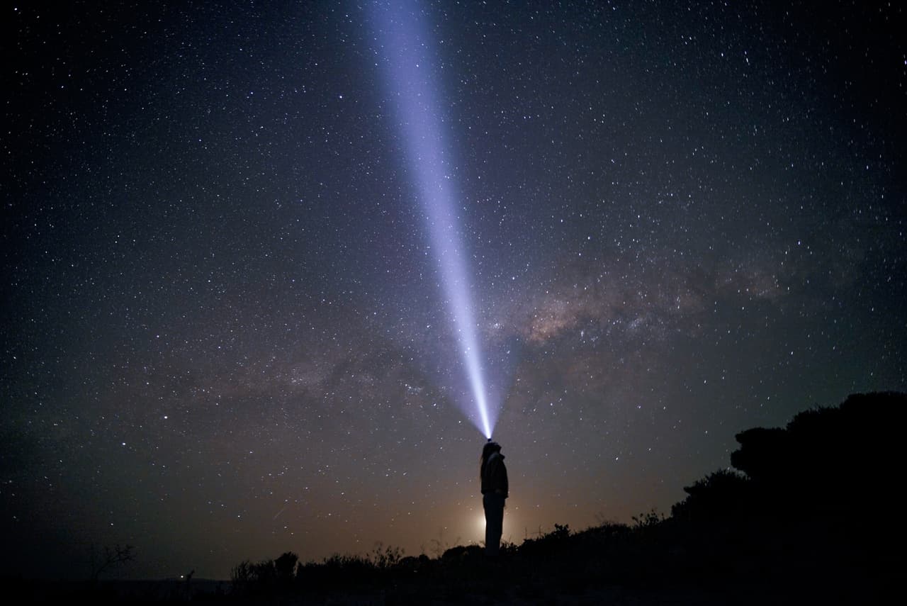 Stargazer with a headlamp under the Milky Way