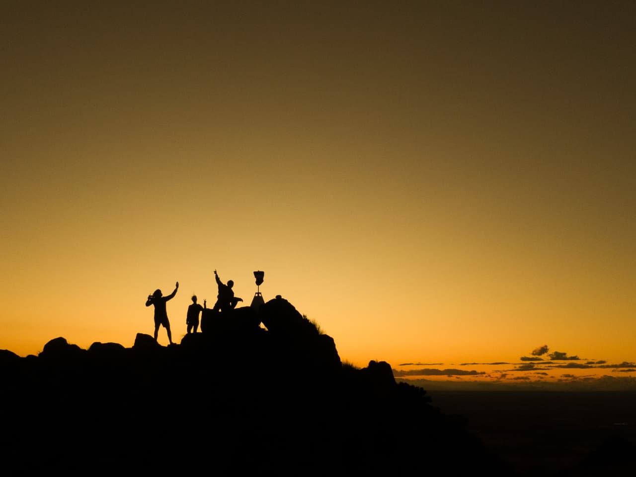 Silhouettes celebrating on a summit at dusk